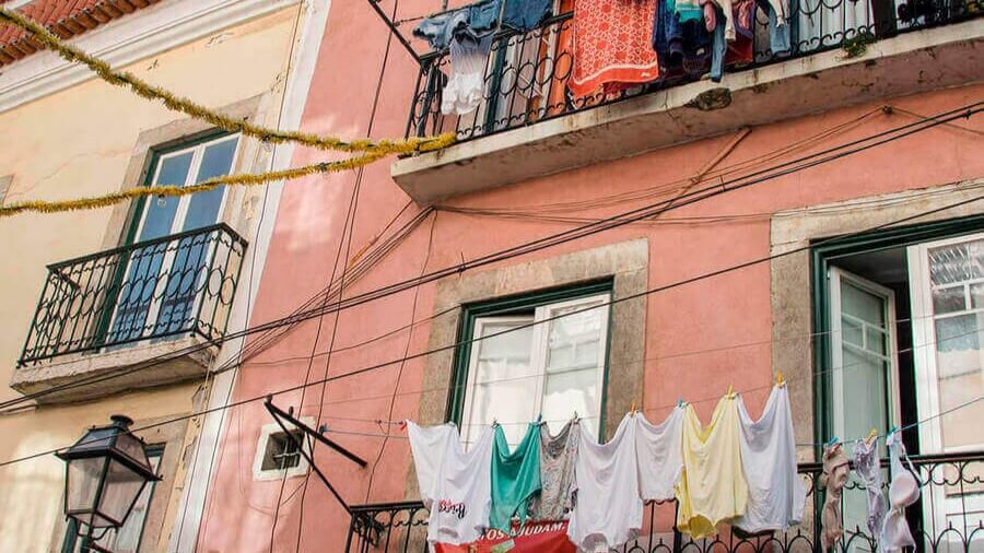 Janelas e varandas com roupa pendurada numa fachada de prédio lisboeta