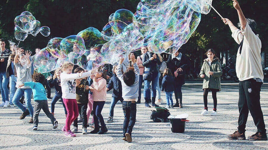 Senhor a fazer bolas de sabão gigantes e várias crianças a brincar